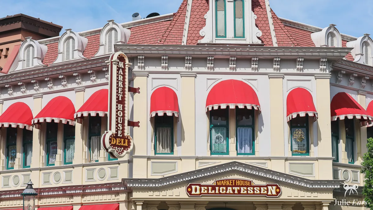 Market House Delicatessen on Main Street U.S.A. at Disneyland Paris, with red awnings, a vertical "Market House Deli" sign and a red tiled roof