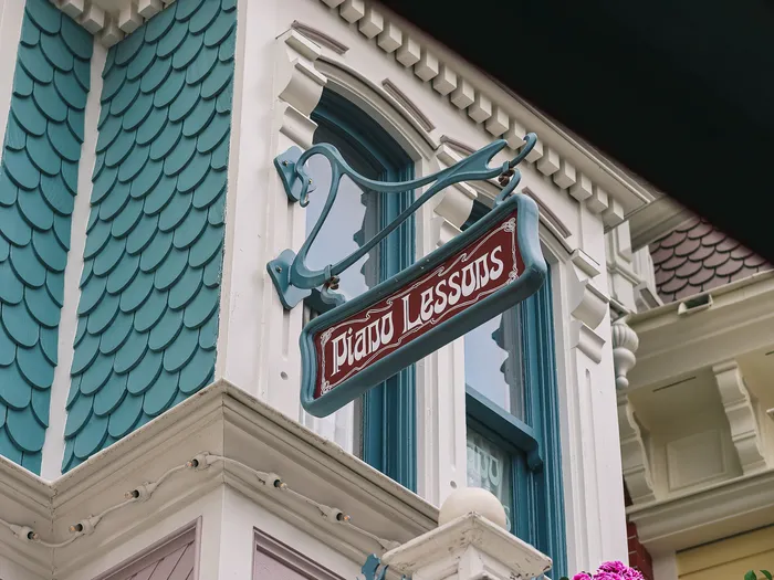 Enseigne Piano Lessons fixée à l’angle d’une façade turquoise à bardeaux, Main Street USA