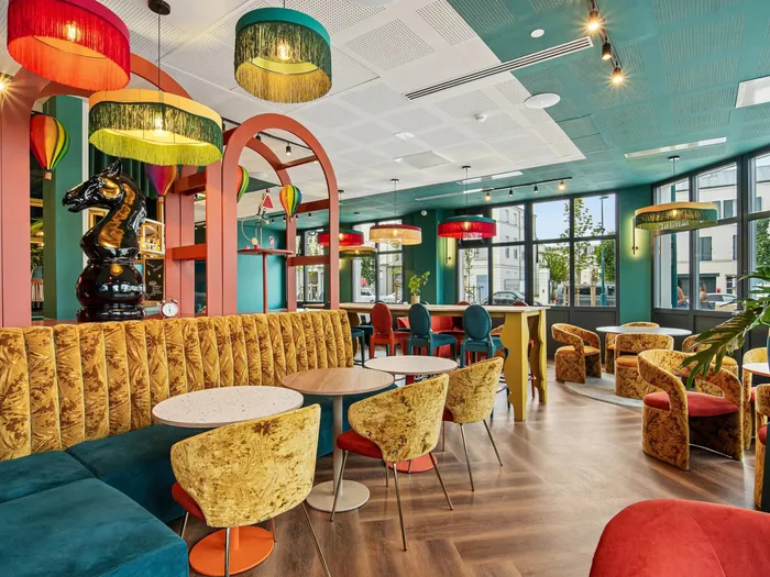 Espace commun de l’Appart Hôtel All Suites Val d’Europe, salon coloré avec banquettes en velours, arches et suspensions à franges.