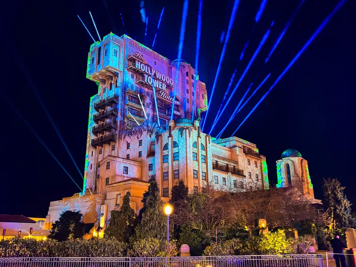Tower of Terror illuminée de projections vertes et bleues et de faisceaux laser dans le ciel nocturne
