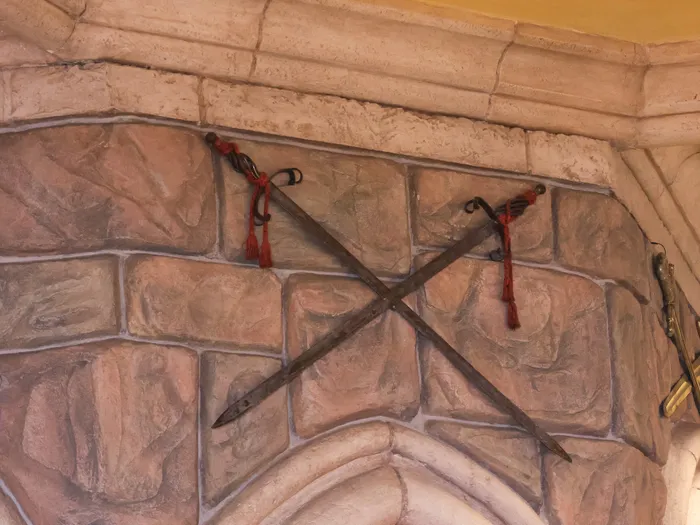 Crossed swords on the stone wall, part of the decor of La Chaumière des Sept Nains at Disneyland Paris.