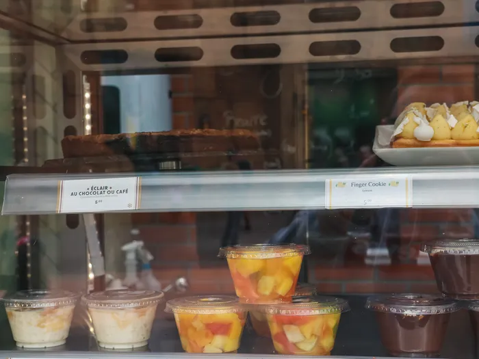 Vitrine réfrigérée du Comptoir présentant salades de fruits, riz au lait et mousses au chocolat.