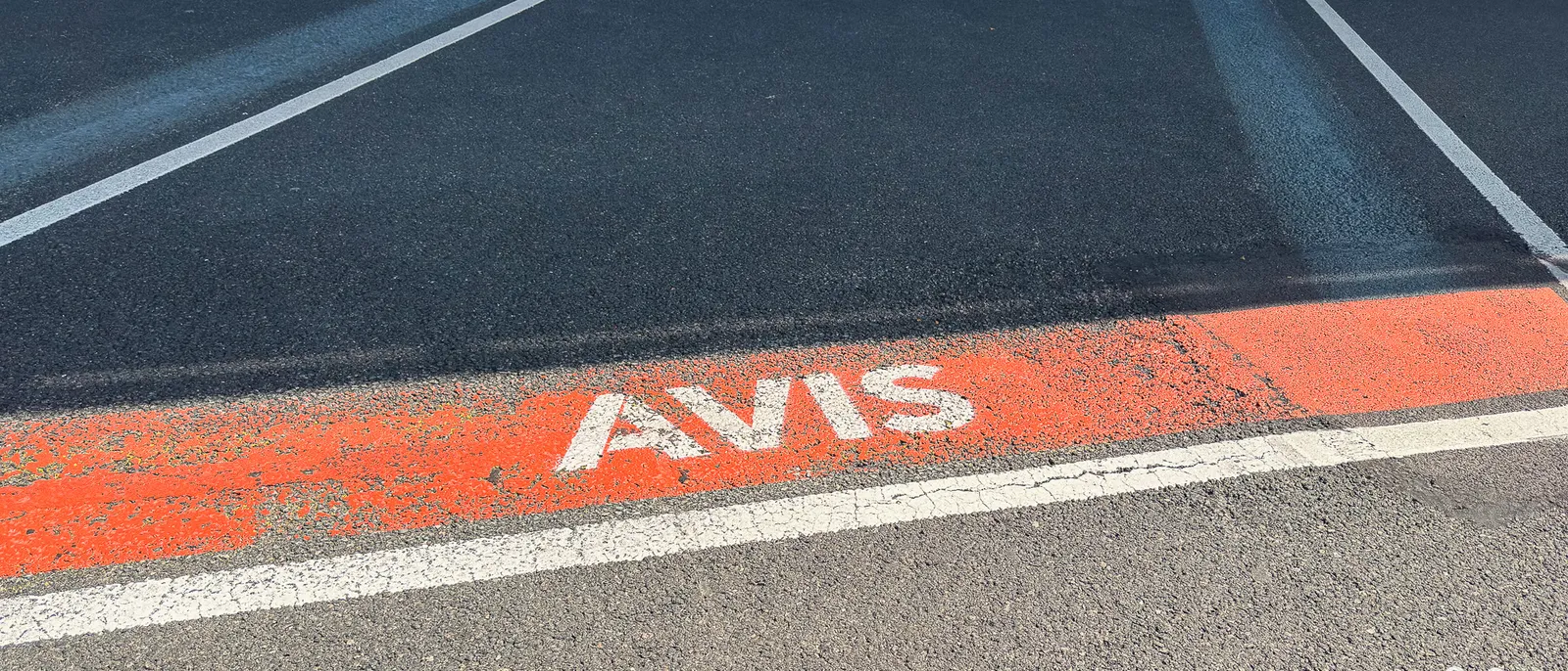 Emplacement de parking au bitume orange avec le mot Avis peint au sol, à Disneyland Paris.