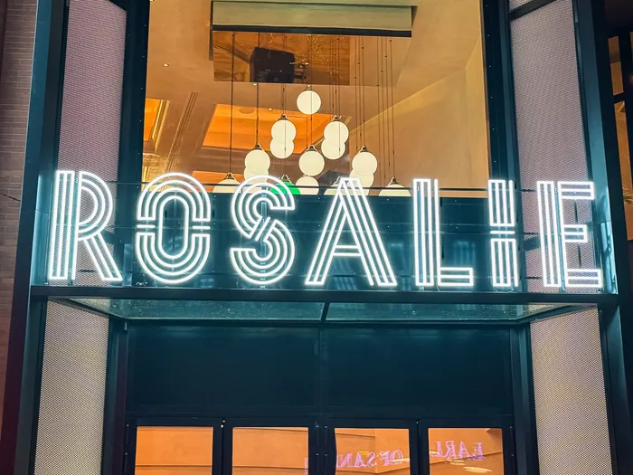 Enseigne néon « Rosalie » éclairée le soir à l’entrée de la brasserie au Disney Village