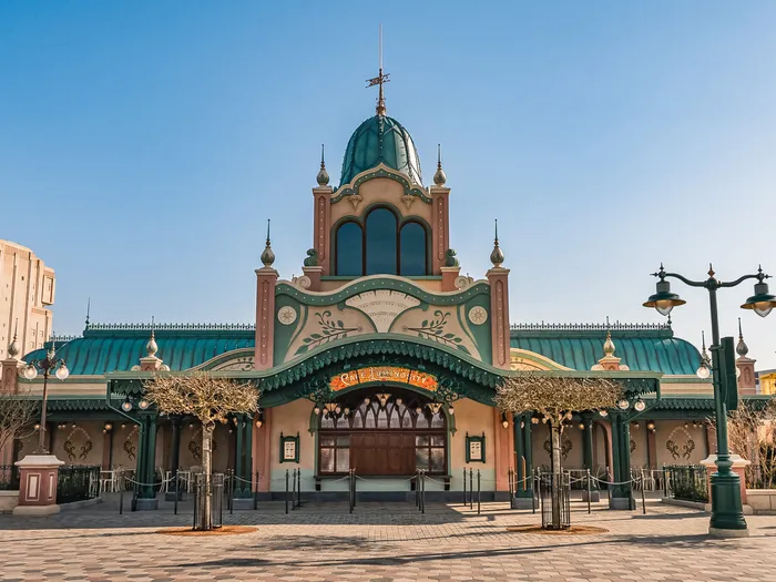 Grand pavillon Art nouveau au dôme vert-de-gris sur la promenade du Parc Disney Adventure World, ciel bleu dégagé.
