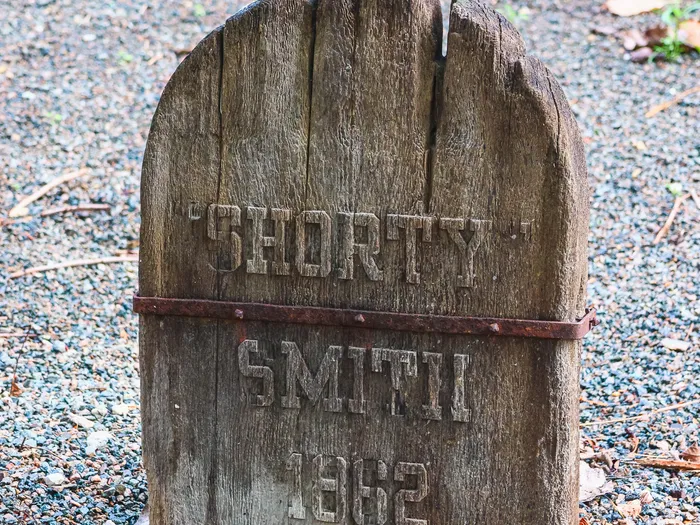 Vieille pierre tombale en bois gravée « Shorty Smith 1862 » cerclée de fer, cimetière de Phantom Manor.