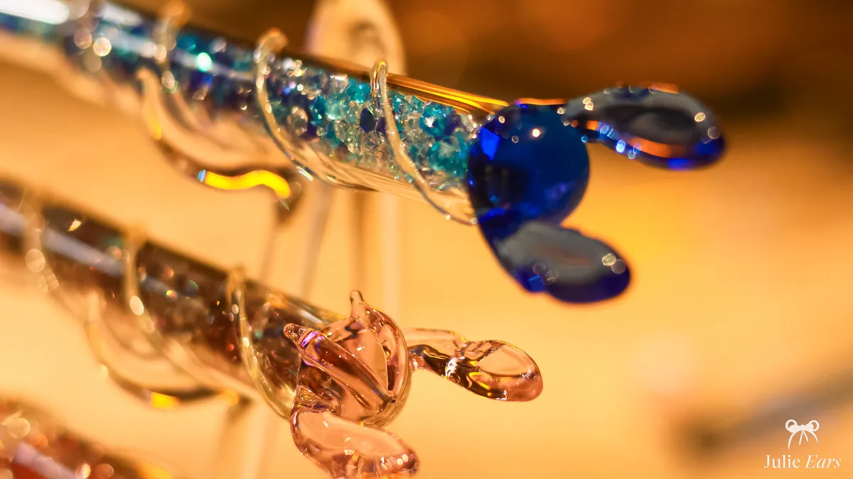 Close-up of blue and pink lampworked glass figurines on display in the Merlin l’Enchanteur shop at Disneyland Paris.