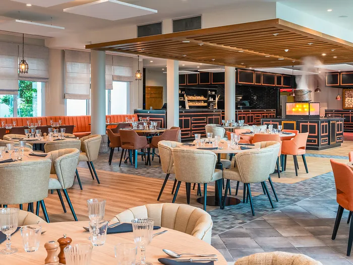 Salle du restaurant du Dream Castle Hotel avec tables rondes dressées et cuisine ouverte au fond.