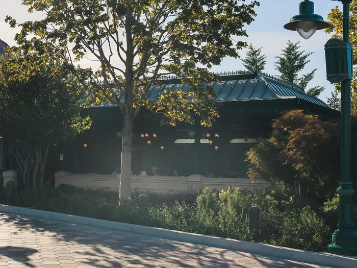 Green-roofed pavilion of La Terrasse Panoramique at Disneyland Paris, surrounded by trees and lamp posts along the path