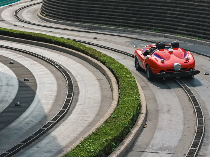 Voiture de sport rouge roulant sur les courbes bétonnées du circuit d’Autopia à Discoveryland.