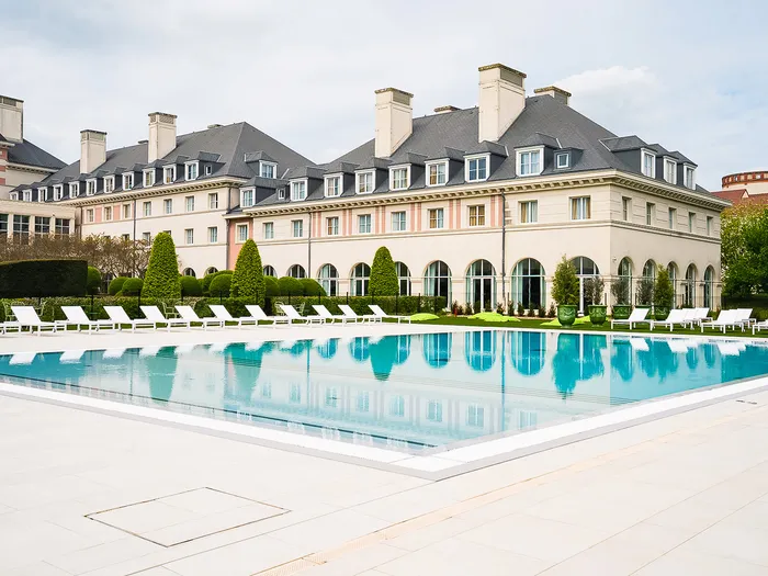Grande piscine extérieure bordée de transats devant la façade du Dream Castle Hotel.
