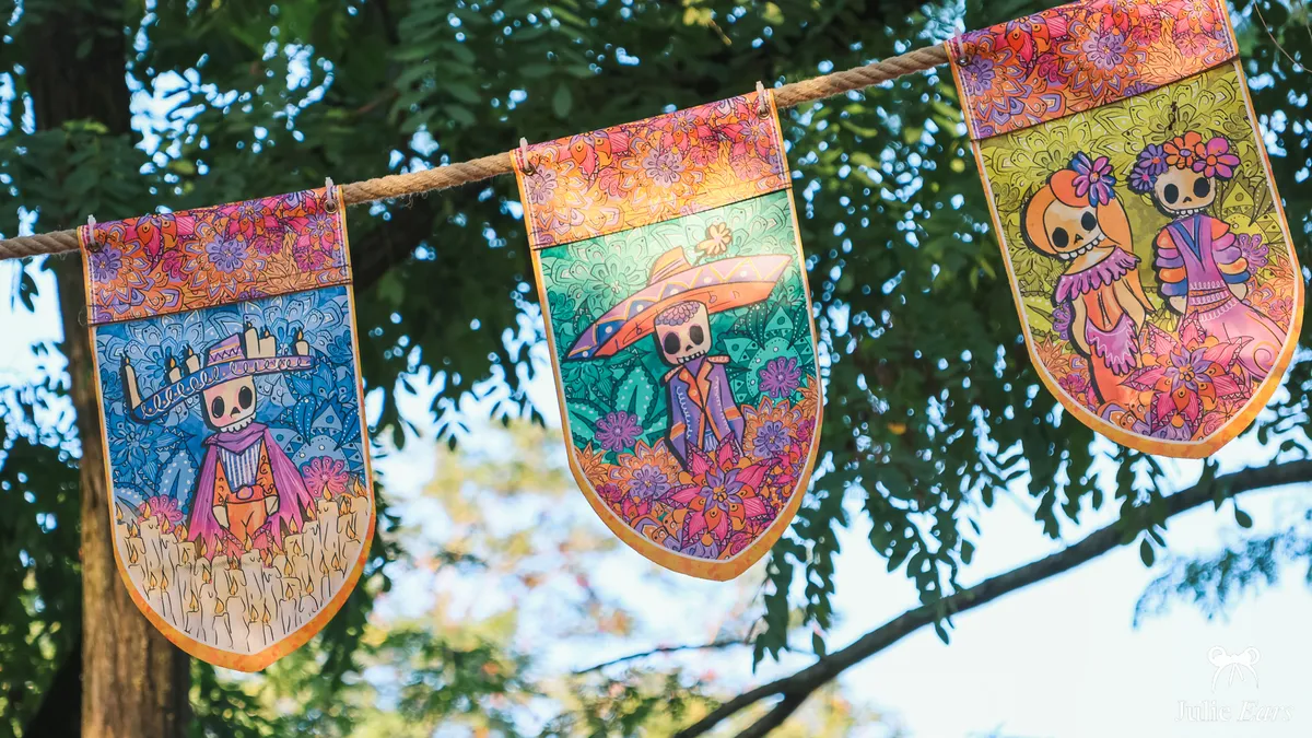 String of Halloween bunting decorated with colourful Mexican skeletons, hung between the trees at Disneyland Paris