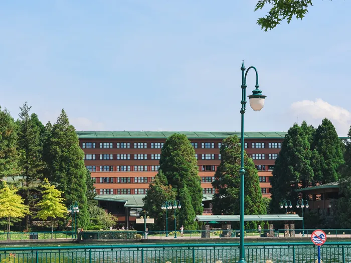 Le Disney Sequoia Lodge en brique et toit vert entouré de séquoias, vu depuis le lac à Disneyland Paris.