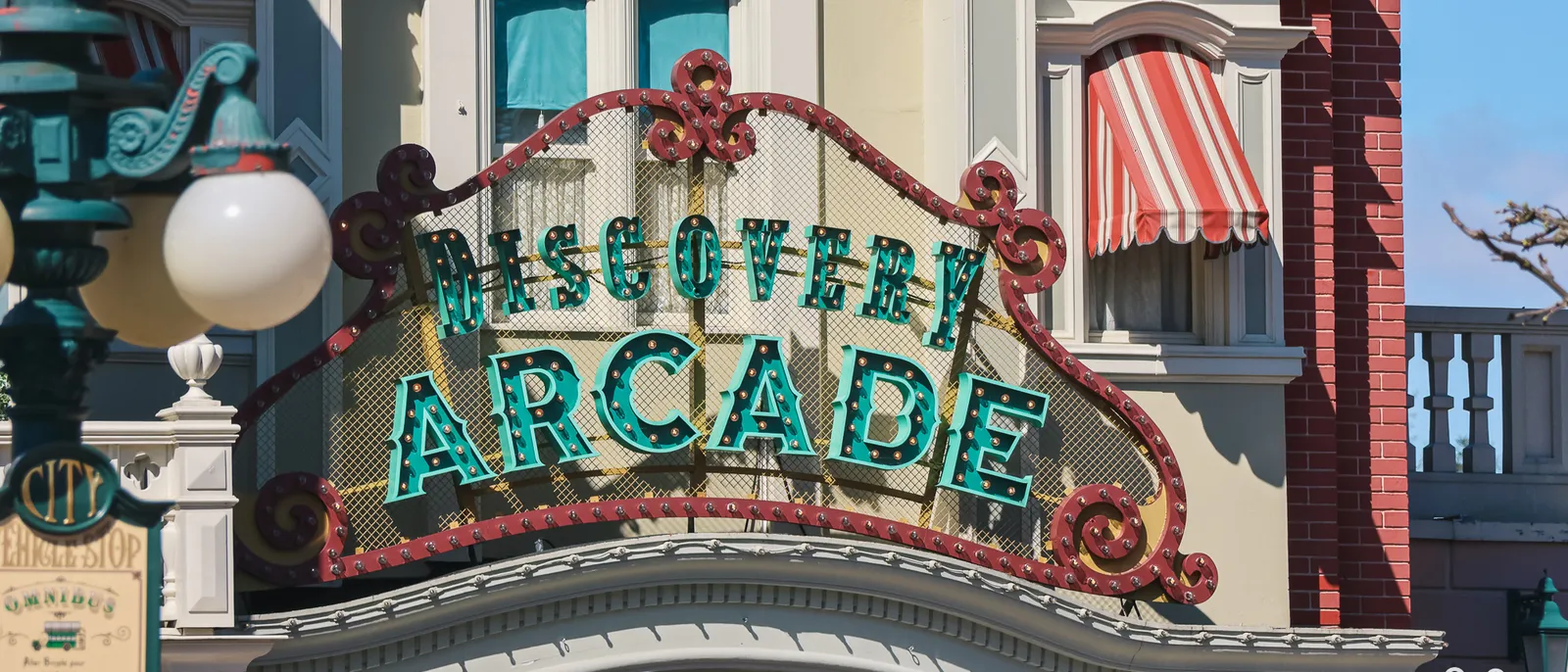 Enseigne verte ouvragée du Discovery Arcade sur une façade victorienne de Main Street, U.S.A. au Parc Disneyland.