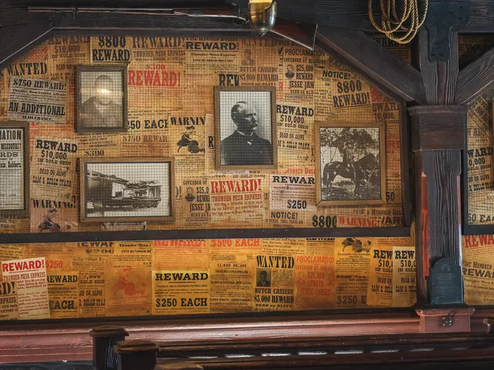 Mur décoré d’affiches western « Wanted » et de portraits encadrés dans le Last Chance Cafe de Frontierland