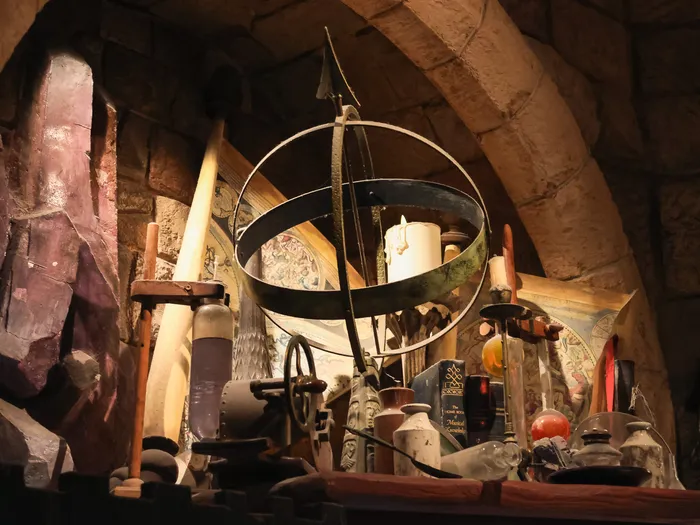 Decor detail in the Merlin l’Enchanteur shop at Disneyland Paris: armillary sphere and candle among crystals and phials, like an alchemist’s workshop.