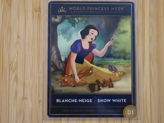Carte à collectionner montrant Blanche-Neige (Snow White) assise en forêt entourée d'oiseaux et d'animaux