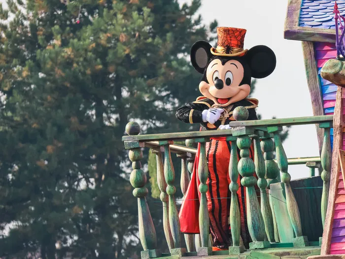 Mickey coiffé d’un haut-de-forme orange à toile d’araignée, sur le balcon coloré d’un char, à la célébration Halloween du Parc Disneyland.
