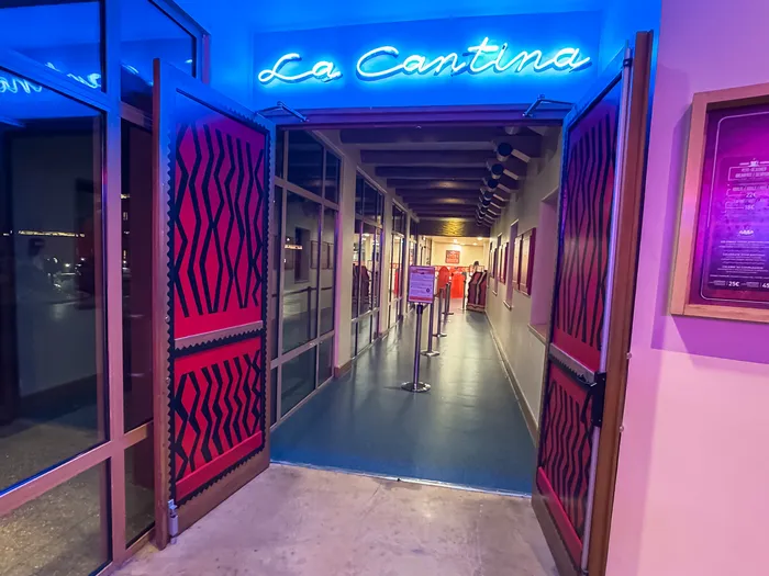 Entrée de La Cantina, enseigne néon bleue et portes tendues de tissu rouge à motifs mexicains, à l’Hôtel Santa Fe