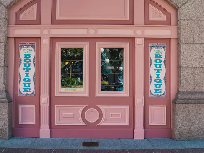 Pink wooden shopfront of the Plaza West Boutique, with two vertical banners framing the windows