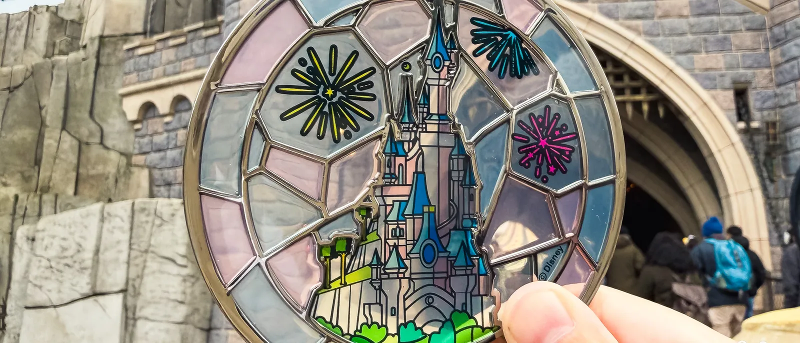Main tenant un sous-verre façon vitrail du château et de feux d’artifice, souvenir Disneyland Paris