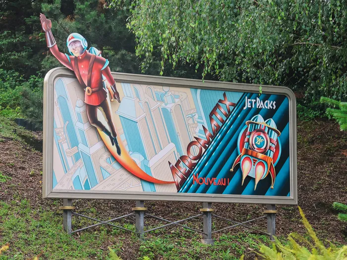 Panneau publicitaire rétro « Astromix Jet Packs Nouveau ! » décorant le parcours d’Autopia, à Discoveryland.