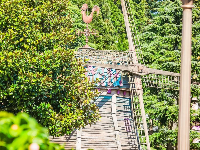 Moulin en bois du restaurant The Old Mill avec sa girouette coq, entouré d’arbres à Fantasyland