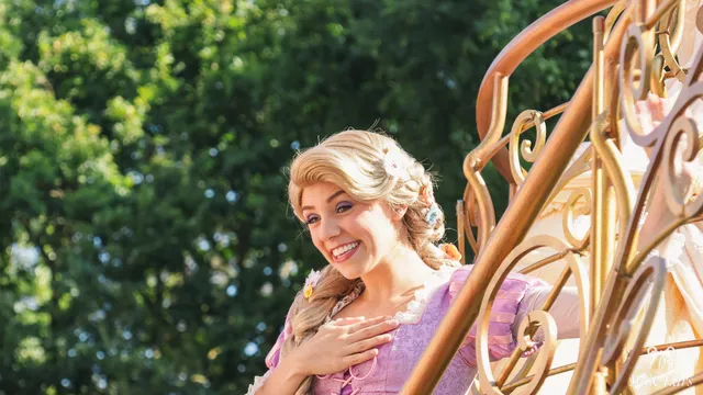 La princesse Raiponce, longue tresse blonde fleurie et robe violette, sur un char doré à Disneyland Paris.