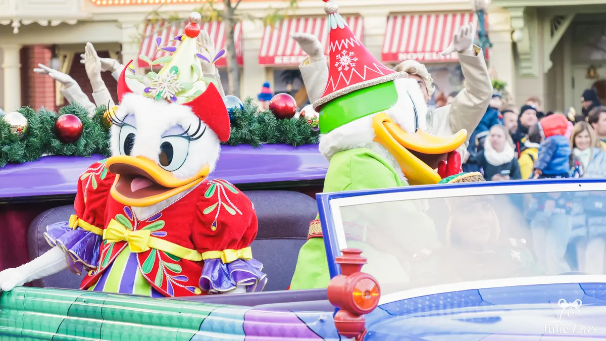Donald et Daisy en tenue de fête saluent les visiteurs depuis une voiture pendant une cavalcade de Noël à Disneyland Paris