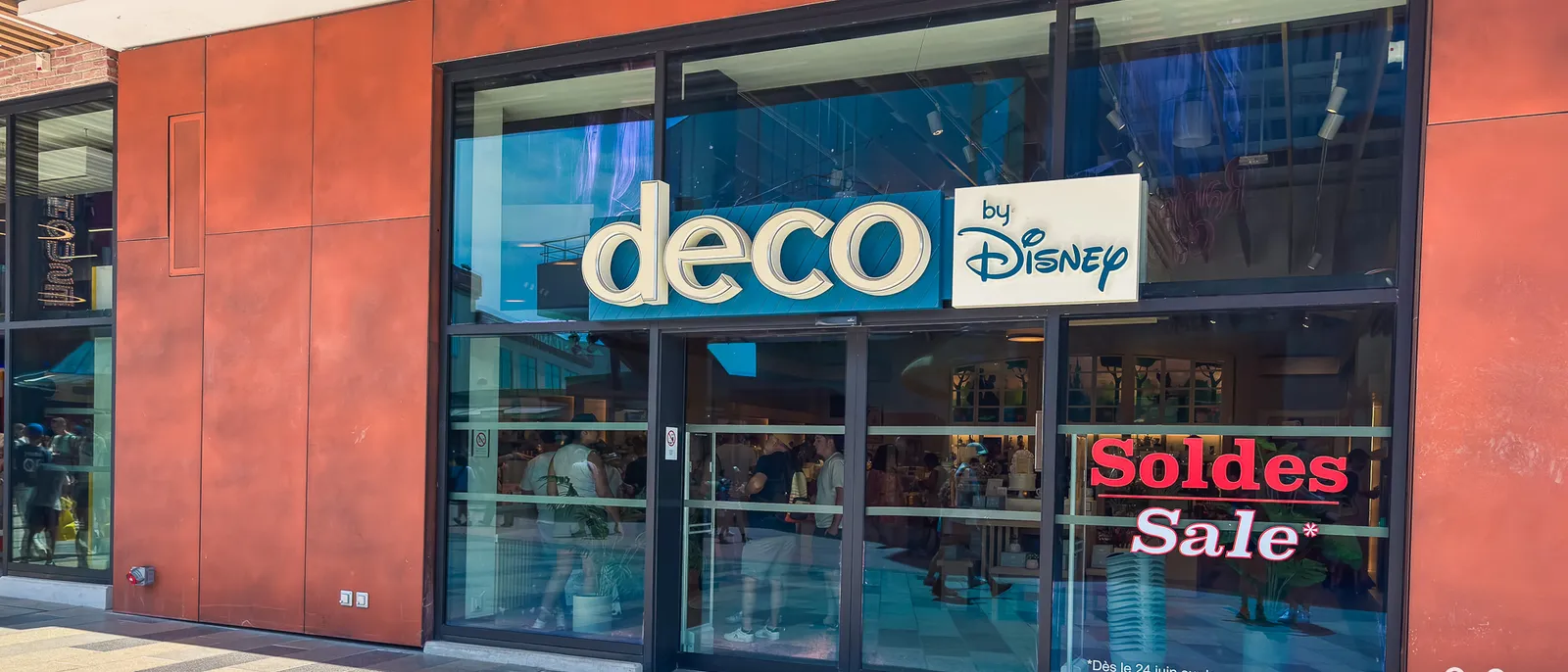 Vitrine de la boutique deco by Disney à Disney Village avec un panneau rouge Soldes Sale.