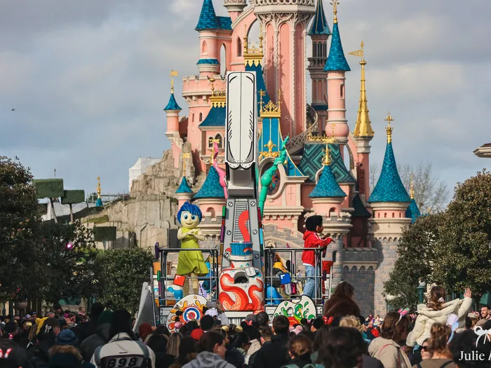 Char pinceau de la parade A Million Splashes of Colour avec Joie devant le château rose de Disneyland Paris.