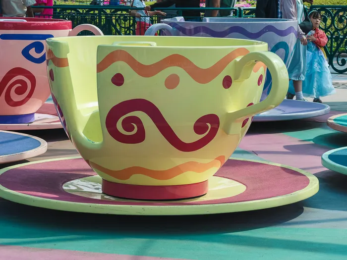 Grande tasse tournante vert anis à motifs orange et rose sur sa soucoupe, attraction Mad Hatter’s Tea Cups à Fantasyland.