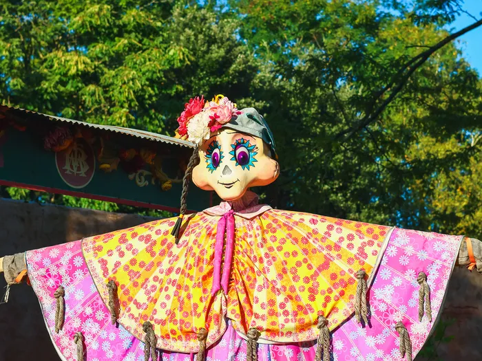 Grande marionnette catrina en poncho fleuri et lanternes colorées, décor du Jour des Morts à Frontierland.