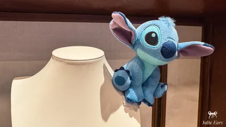 Stitch shoulder plush, the blue character from Lilo and Stitch, sitting on the edge of a shop window.