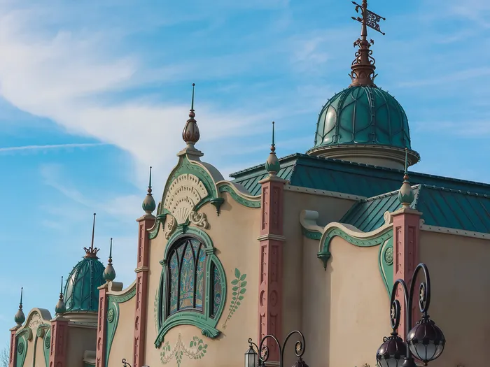 Façade Art nouveau du Regal View Restaurant, dômes verts et vitraux, sous un ciel bleu au Parc Disney Adventure World.