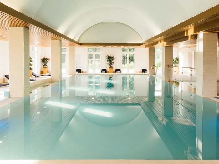 Piscine intérieure sous voûte blanche avec transats et plantes au Grand Magic Hotel.