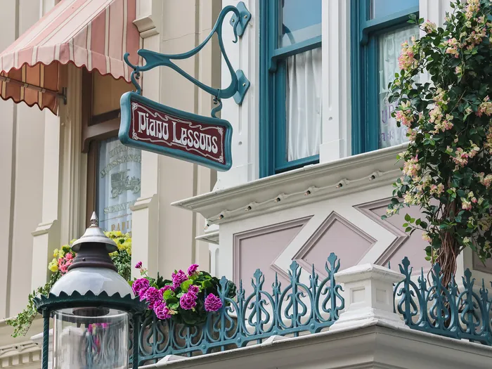 Enseigne fer forgé Piano Lessons et fleurs sur une façade de Main Street près de The Ice Cream Company