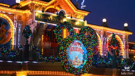 La gare de Main Street décorée pour Noël, grande couronne en forme de Mickey et guirlandes lumineuses, la nuit, à Disneyland Paris