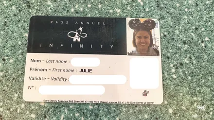 Julie’s Disneyland Paris Infinity annual pass card, with the Infinity logo and her photo wearing a Minnie ears headband.
