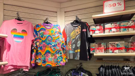 Disney and Marvel T-shirts on display in a shop under a red 50% off sign at Disneyland Paris.