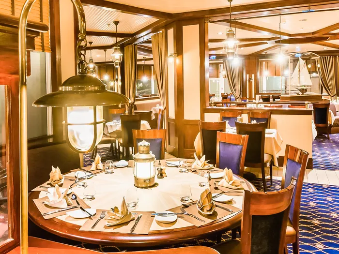 Table ronde dressée du Yacht Club, serviettes pliées en éventail et lanterne marine au centre