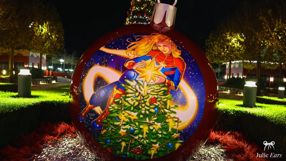 Giant Christmas bauble showing Captain Marvel placing a gold star on a tree, at night at Disney Hotel New York - The Art of Marvel