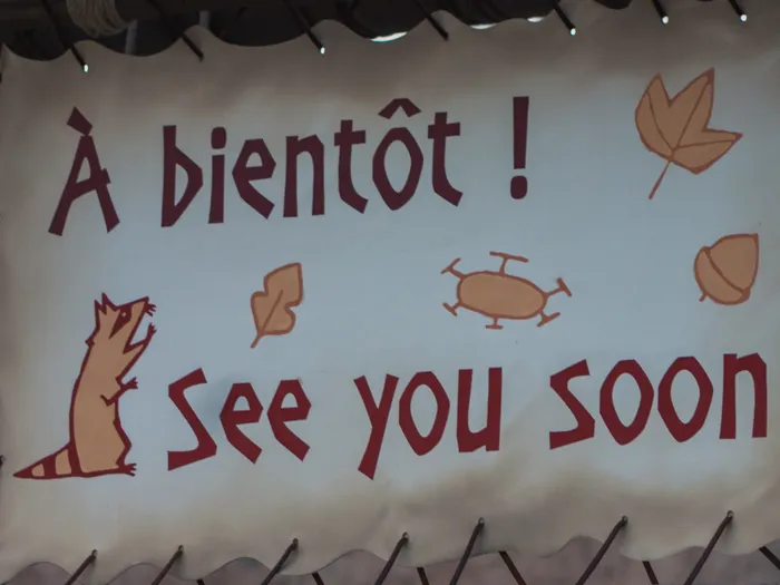 Pancarte de sortie « À bientôt ! See you soon! » ornée d’un raton laveur à l’aire de jeux de Frontierland