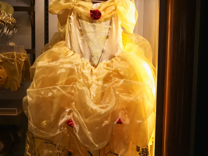 Robe jaune de Belle avec rose rouge, présentée sur cintre à la boutique Mon Rêve Royal