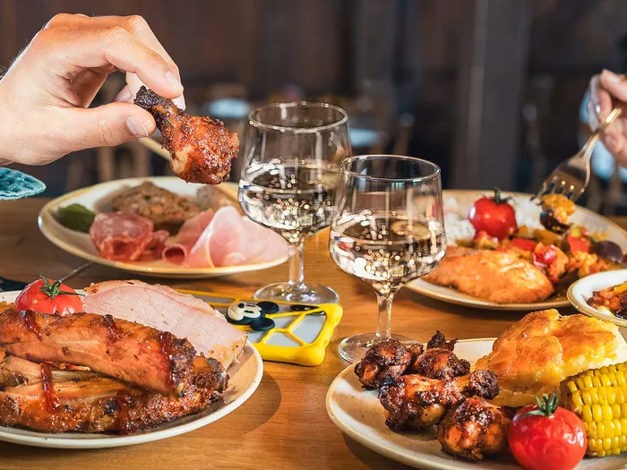 Table garnie de travers de porc, maïs grillé, ailes de poulet et vin blanc au restaurant La Grange