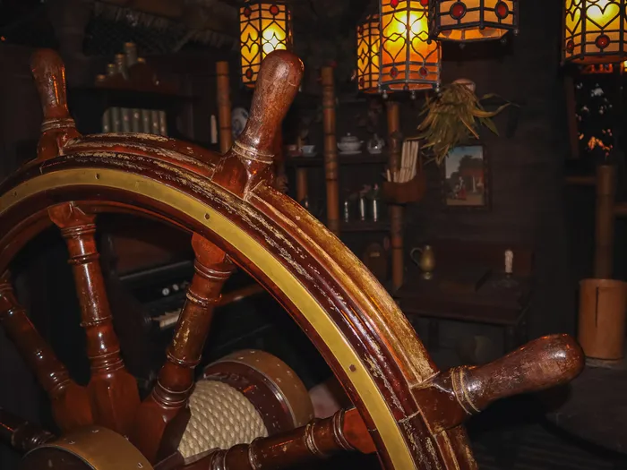 Grande roue de gouvernail en bois éclairée par des lanternes vitraux dans le décor de La Cabane des Robinson