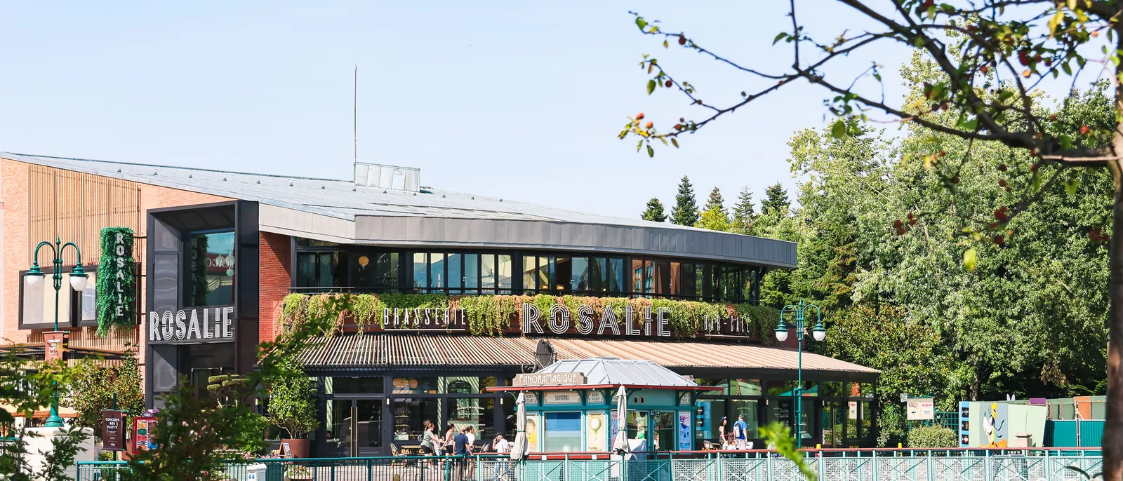 Restaurant Rosalie et sa terrasse au bord du lac du Disney Village, sous un ciel bleu, entourés d’arbres