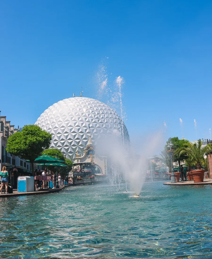 Grande sphère géodésique blanche au bord d’un lac avec jet d’eau, sous un ciel bleu à Europa-Park