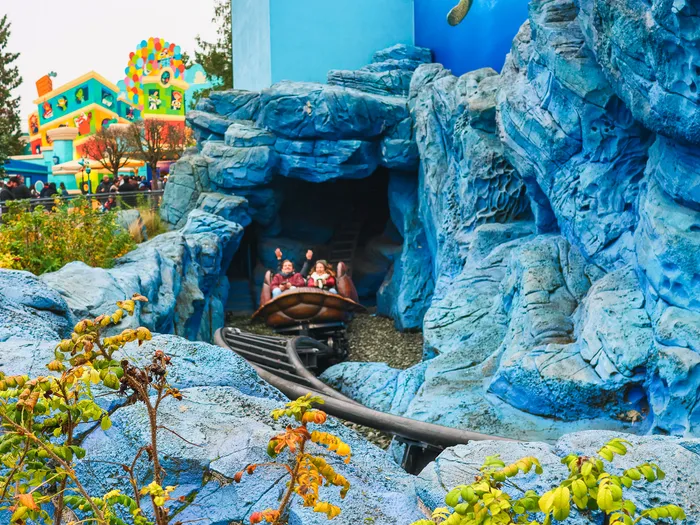 Wagon en forme de carapace de tortue avec passagers, sortant d’un tunnel de rochers bleus de Crush’s Coaster.