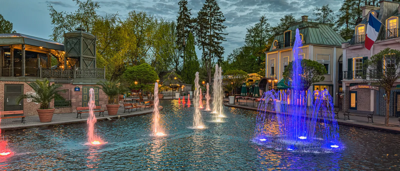 Fontaines illuminées de couleurs dans un bassin à la tombée de la nuit à Europa-Park